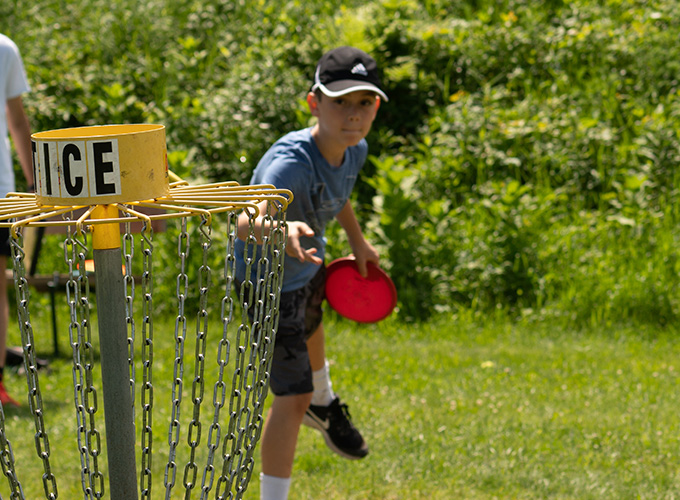 A camper aims a frisbee disc at a wicker during a game of frisbee golf at North Star Camp for Boys.