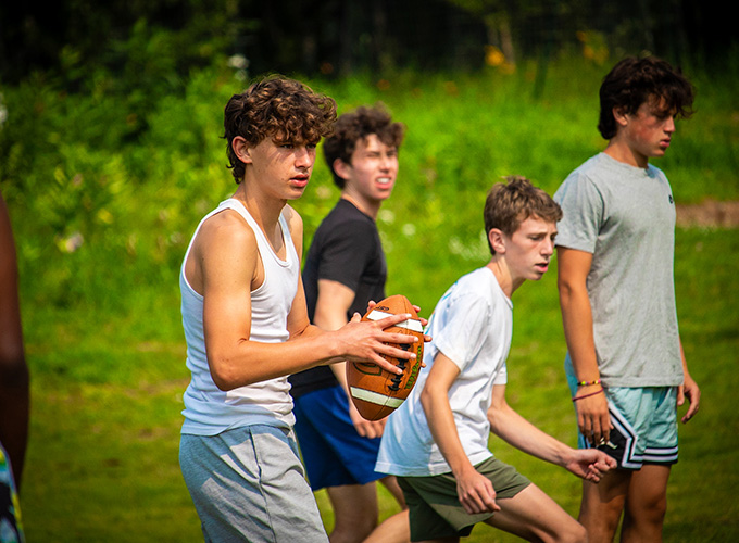 A boy gets ready to throw a football while his teammates assess their opponents during a game at North Star Camp for Boys.