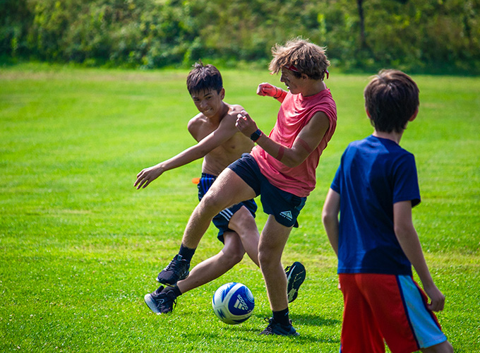 Two campers kick while competing for a soccer ball during a game at North Star Camp for Boys.