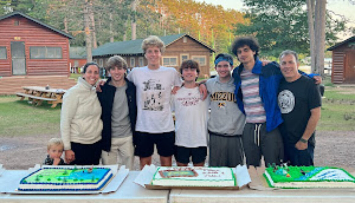 A group of camp staff pose for a photo behind three decorated sheet cakes.