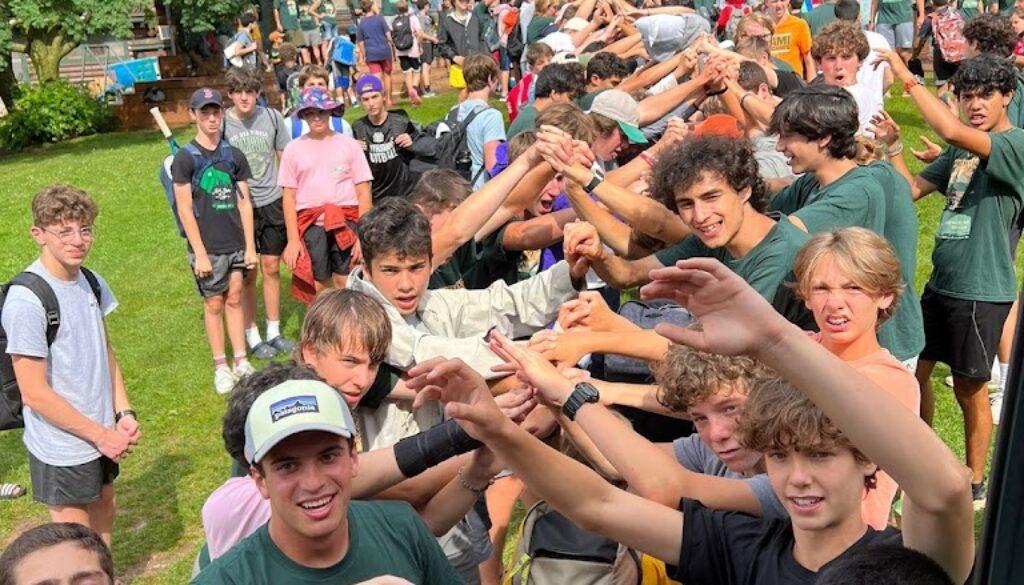 A group of campers and staff members at North Star Camp for Boys participate in a camp tradition of welcoming incoming campers coming off the bus.