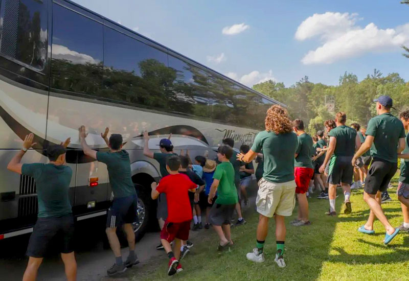 A group of counselors and campers at North Star Camp for boys run to a bus awaiting to greet camp newcomers.