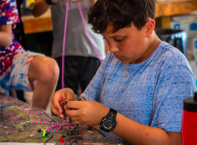 A camper at North Star Camp for Boys participates in a craft activity making friendship bracelets from re-used materials.