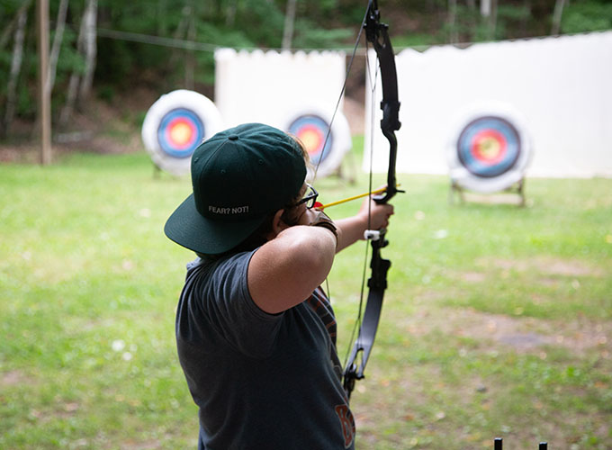 A camper aims a bow and arrow at an archery target at North Star Camp for Boys.
