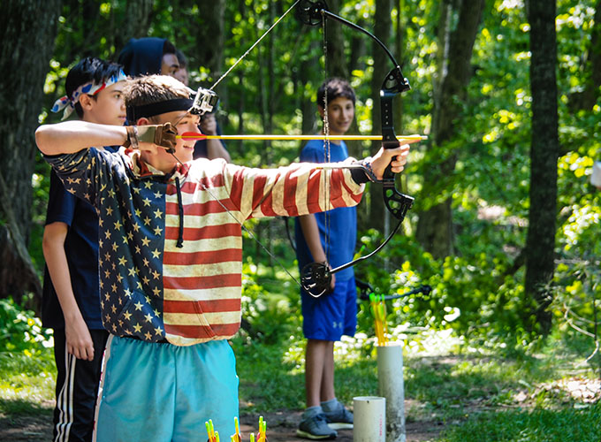 A camper aims an arrow, while pulling the strings of a bow during an archery activity session at North Star Camp for Boys.