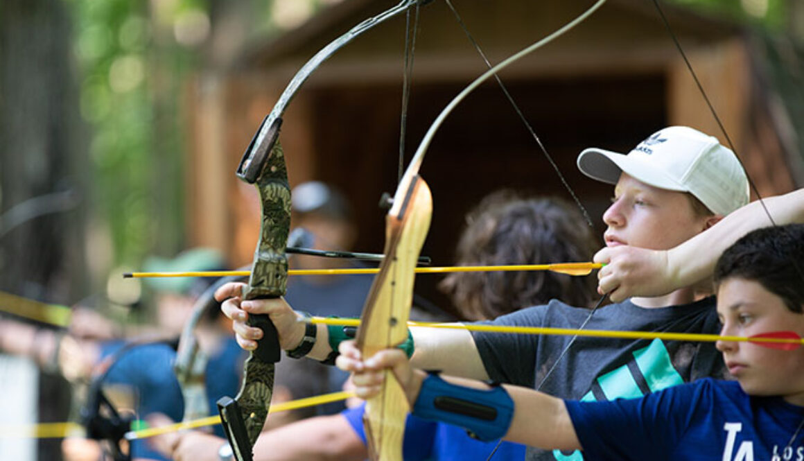 Campers pull back the strings on an archery bow and aim their arrows during archery training at North Star Camp for Boys.