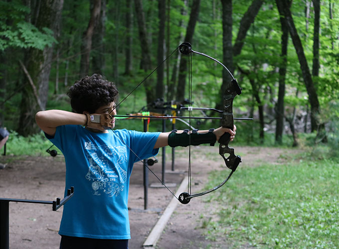 A camper pulls back the strings of a bow while aiming the arrow during an archery activity at North Star Camp for Boys.
