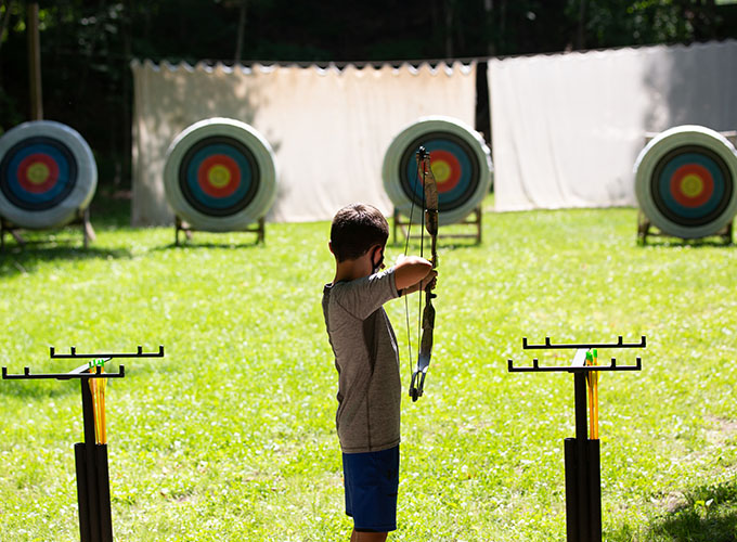 A camper aims a bow and arrow at a bullseye at North Star Camp for Boys.