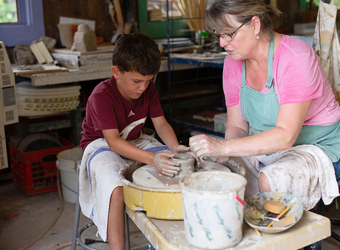 A camper learns how to use a pottery wheel with the help of an instructor at North Star Camp for Boys.