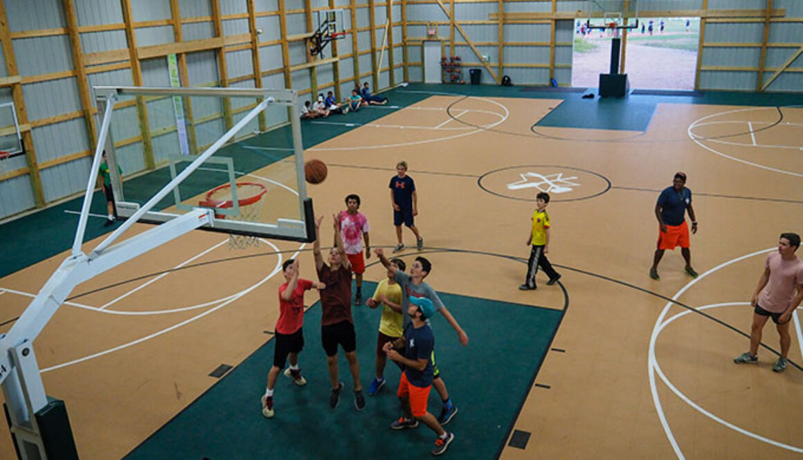 A group of campers play a game of basketball and try to block the ball from going into the hoop at North Star Camp for Boys.