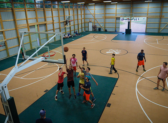 A group of campers play a game of basketball and try to block the ball from going into the hoop at North Star Camp for Boys.
