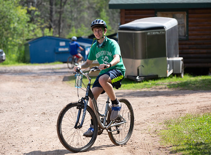A camper rides his bike through a trail on the grounds of North Star Camp for Boys.