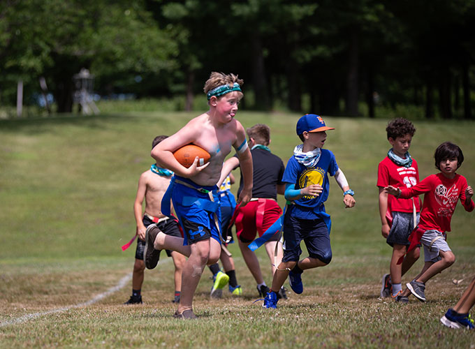 A camper carries a football as other campers run alongside him during a game at North Star Camp for Boys.