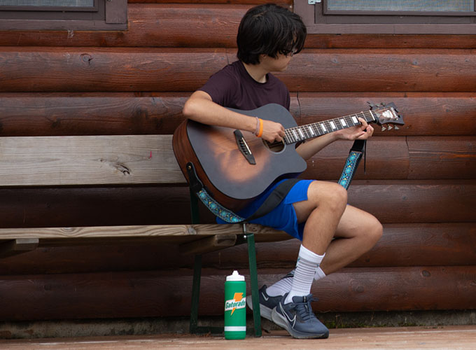 A camper strums an acoustic guitar at North Star Camp for Boys.