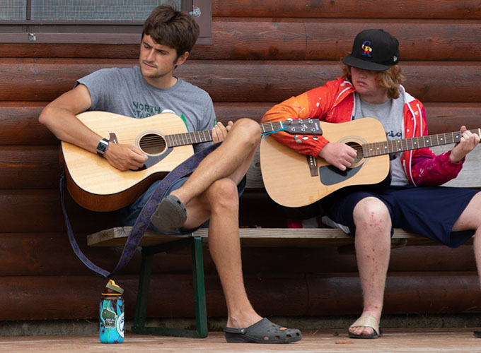 Two campers at North Star Camp for Boys strum on guitars.