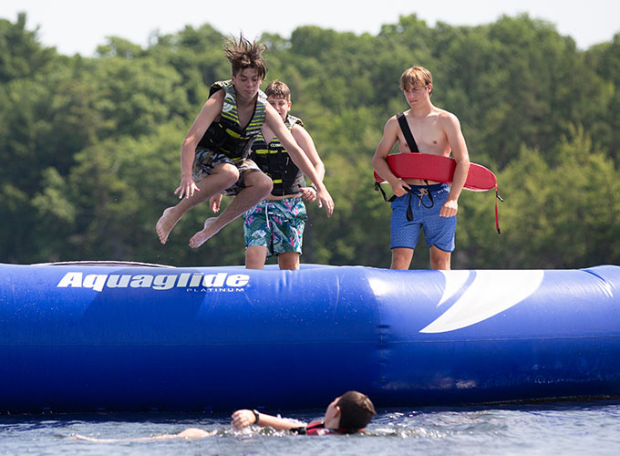 A boy jumps off the water trampoline into Spider Lake at North Star Camp for Boys.