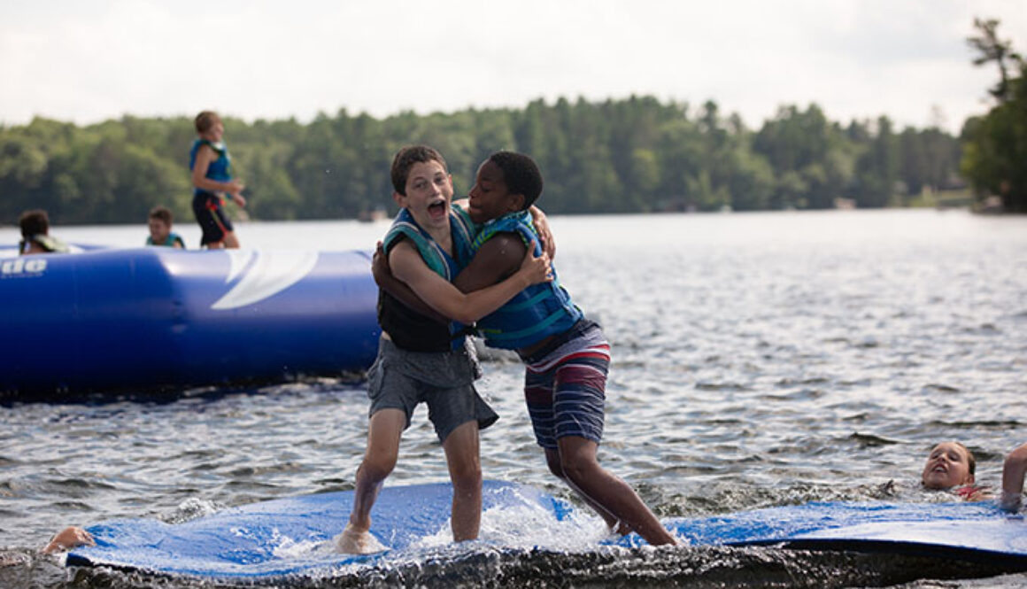 Two boys play on the splash pad in Spider Lake at North Star Camp for Boys.