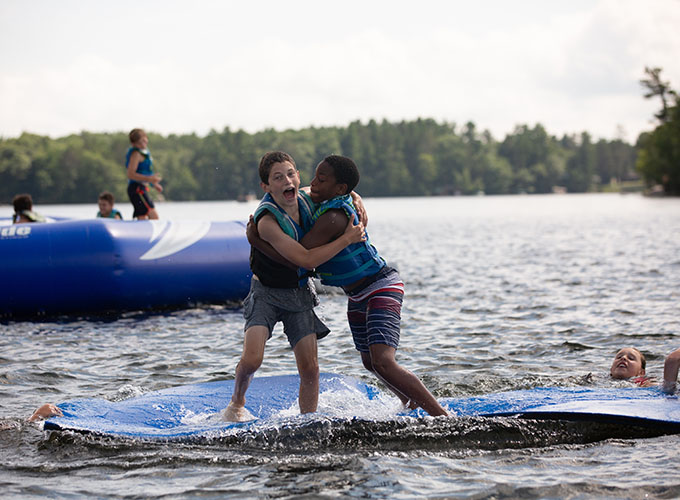 Two boys play on the splash pad in Spider Lake at North Star Camp for Boys.