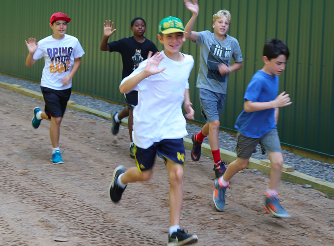 A group of campers wave while running cross country at North Star Camp for Boys.