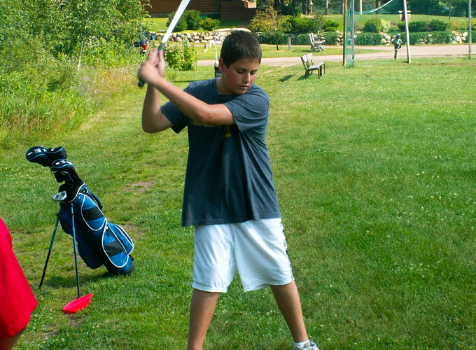 A camper is about to swing a golf club at North Star Camp for Boys.