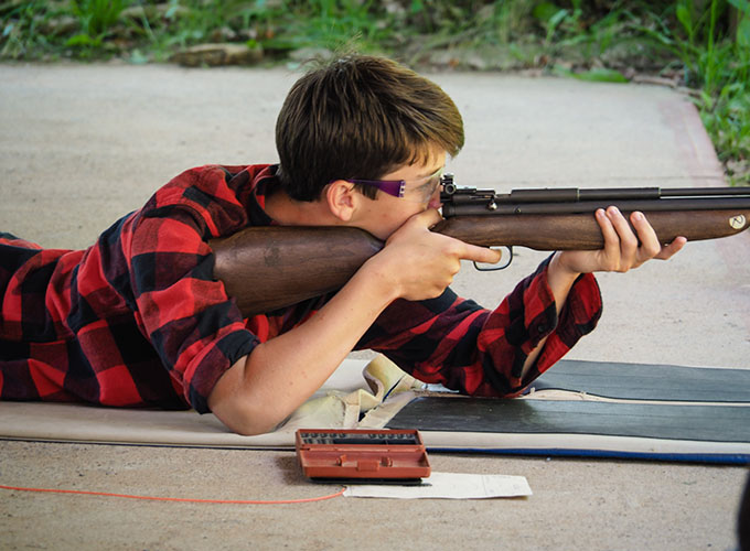 A boy aims a rifle during a riflery activity session at North Star Camp for Boys.