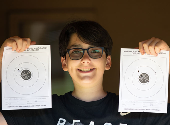 A camper holds up the rifle target bullseyes he was aiming at to show off his riflery skills at North Star Camp for Boys.