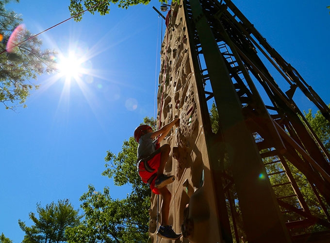A camper makes his next move as he is half-way up the rock climbing wall at North Star Camp for Boys.