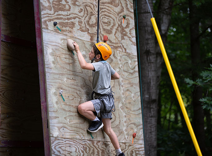 A camper climbs up a rock wall at North Star Camp for Boys.