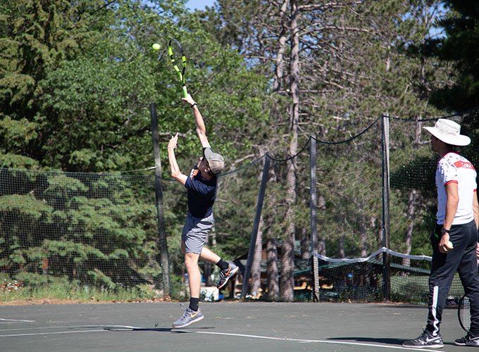 A camper jumps in the air to spike a tennis ball at North Star Camp for Boys.