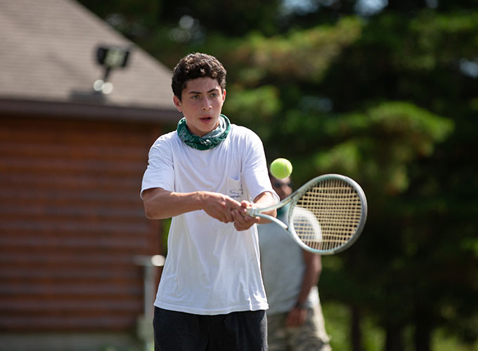 A camper gets ready to hit a tennis ball at North Star Camp for Boys.
