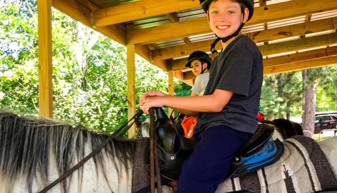 A North Star Camp for Boys camper smiles while on horseback.