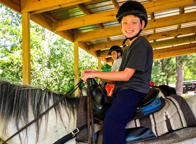 A North Star Camp for Boys camper smiles while on horseback.