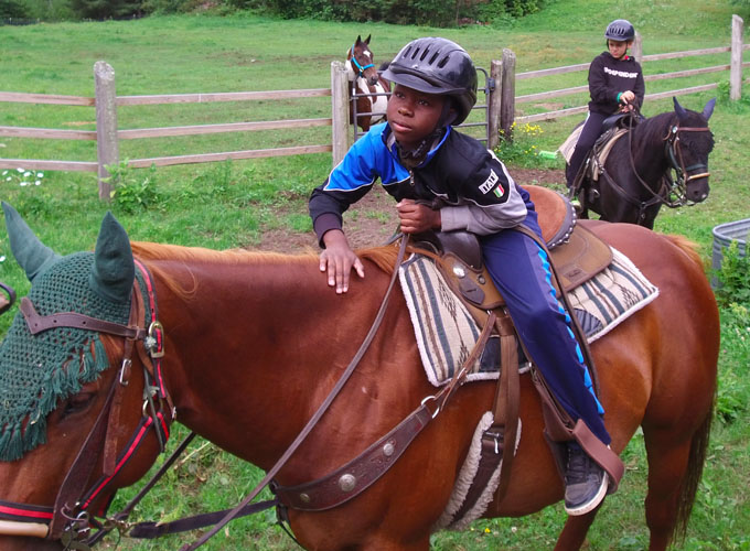 A camper from North Star Camp for Boys holds onto the reins while horseback riding.