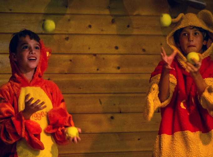 Two campers at North Star Camp for Boys dressed in Winnie the Pooh onesies showcase their juggling skills during an improv activity.