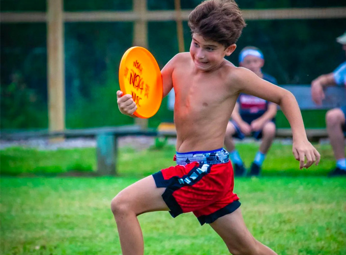 A camper at North Star Camp for Boys is running with a frisbee in hand during a game of Ultimate Frisbee.