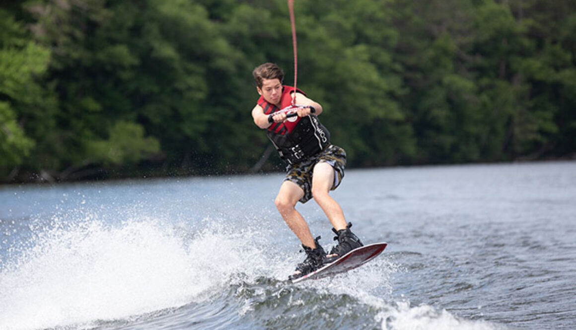 A camper practices a wakeboarding jump in Spider Lake at North Star Camp for Boys.