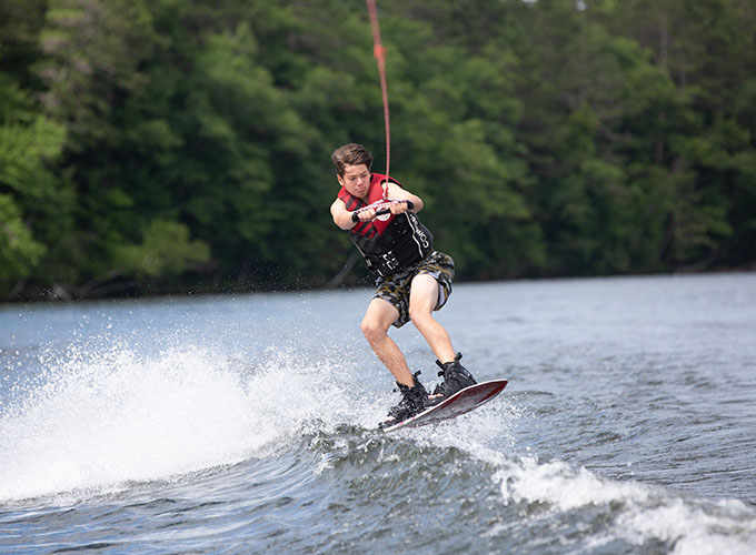 A camper practices a wakeboarding jump in Spider Lake at North Star Camp for Boys.