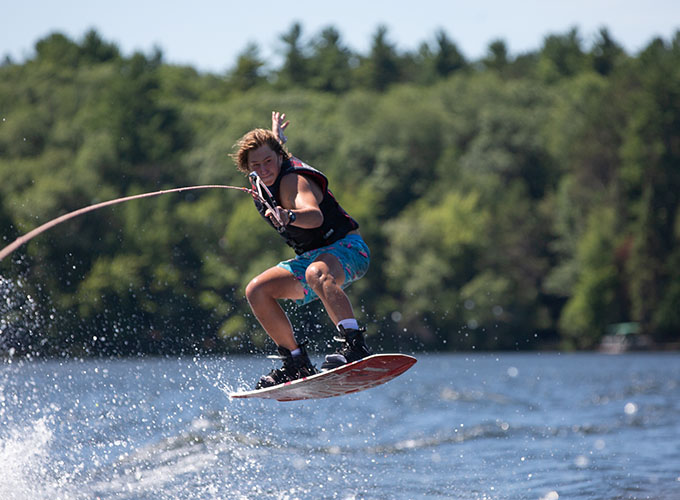 A camper performs a wakeboard jumping trick as he glides through the air at North Star Camp for Boys.