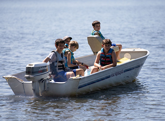 Five campers wearing life jackets leisurely sit in a speedboat on Spider Lake at North Star Camp for Boys.