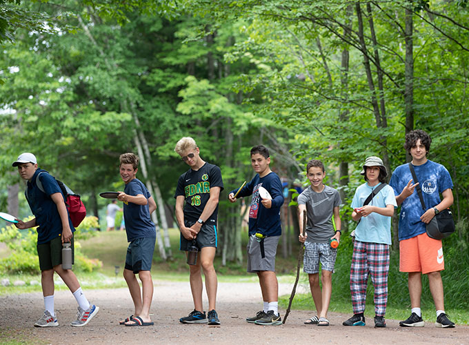 A line of seven campers at North Star Camp for Boys strike a pose in between a round of disc golf.