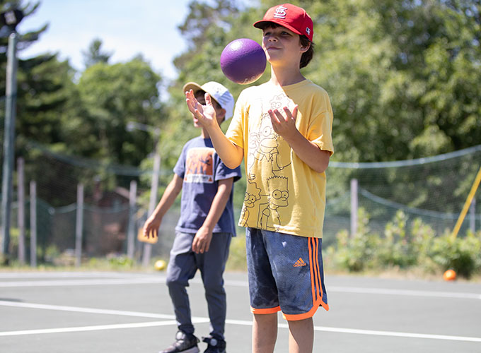 A camper tosses a purple foam ball in the air in between rounds of dodgeball at North Star Camp for Boys.