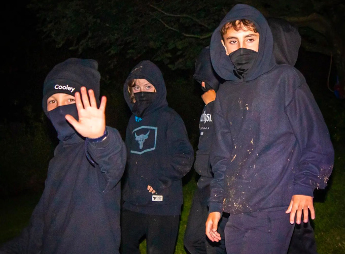 A group of campers wearing all black and facemasks participate in a game of Espionage at North Star Camp for Boys.