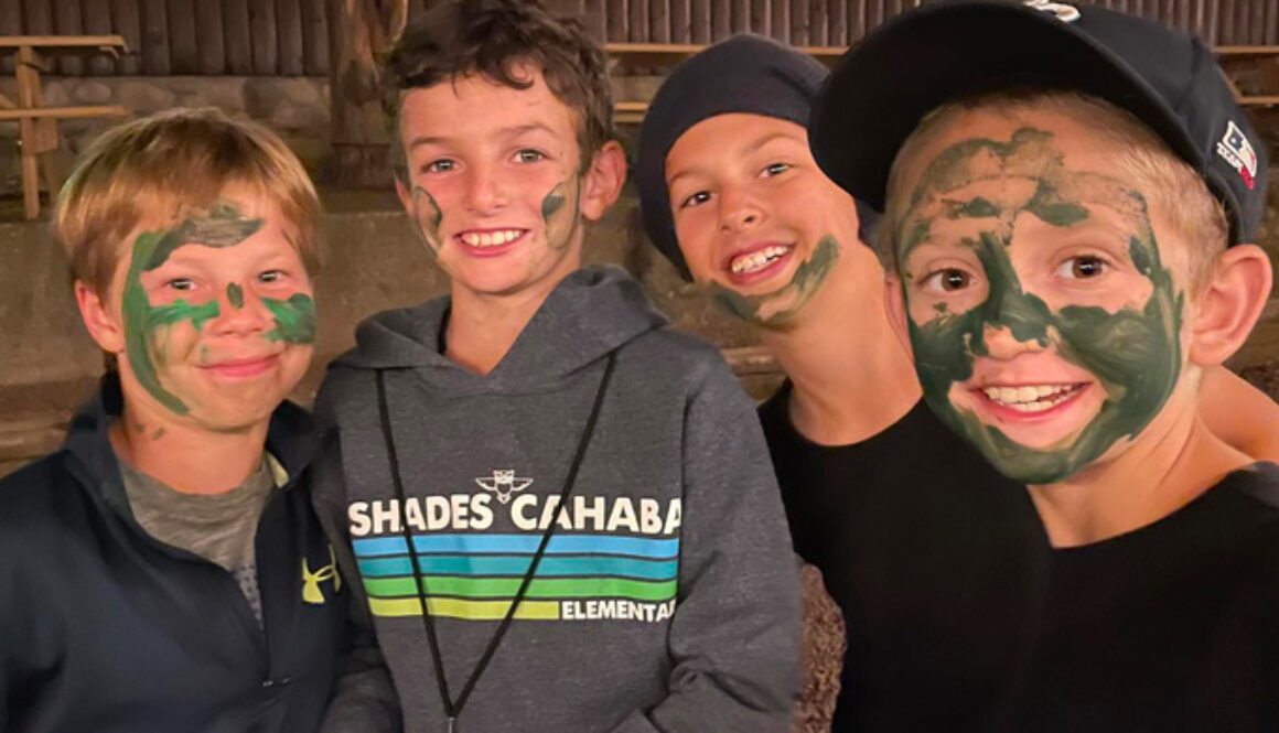 A group of campers smile for a photo wearing green face paint during a game of Espionage at North Star Camp for Boys.