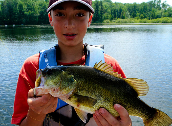 A camper holds up the fish he caught out of Spider Lake at North Star Camp for Boys.