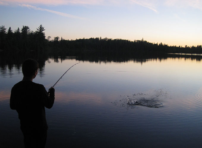 A boy makes a splash in Spider Lake by throwing a fishing line into the water at North Star Camp for Boys.
