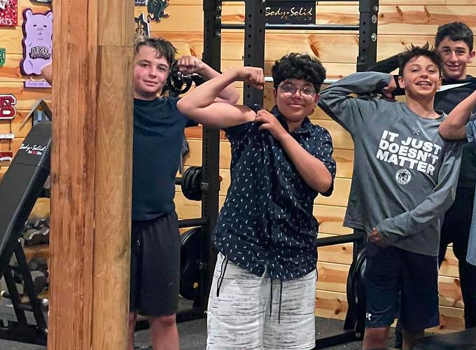 Campers pose for a photo by showing off their arm muscles at the gym at North Star Camp for Boys.