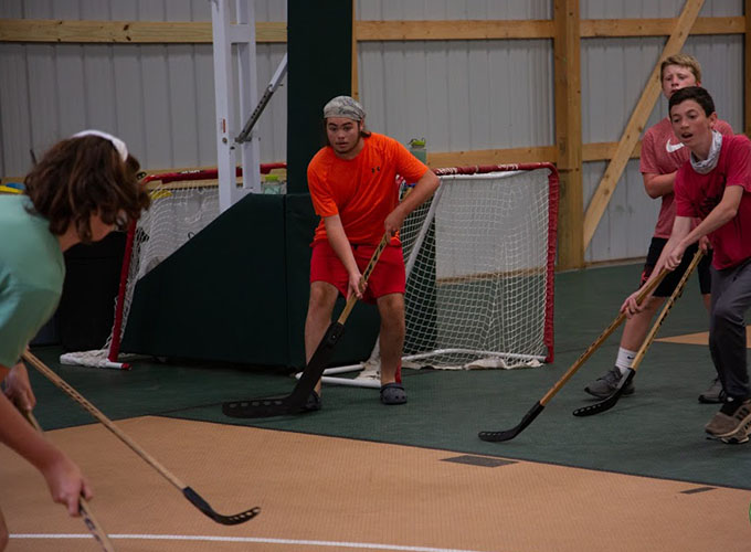 Campers hold hockey sticks waiting to intercept the ball during a floor hockey activity in Victory Fieldhouse at North Star Camp for Boys.