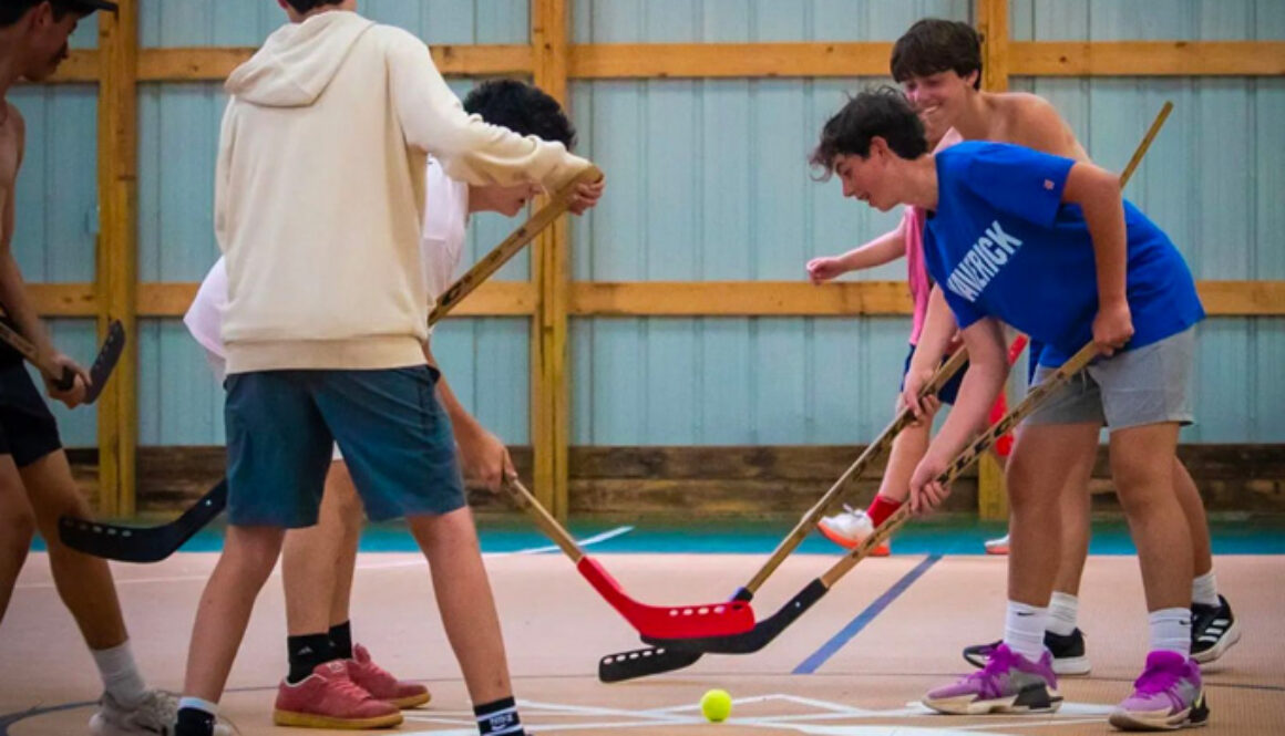 Campers hit tennis ball with hockey sticks during a game of floor hockey at North Star Camp for Boys.