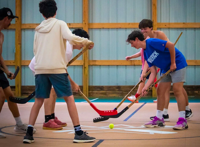 Campers hit tennis ball with hockey sticks during a game of floor hockey at North Star Camp for Boys.