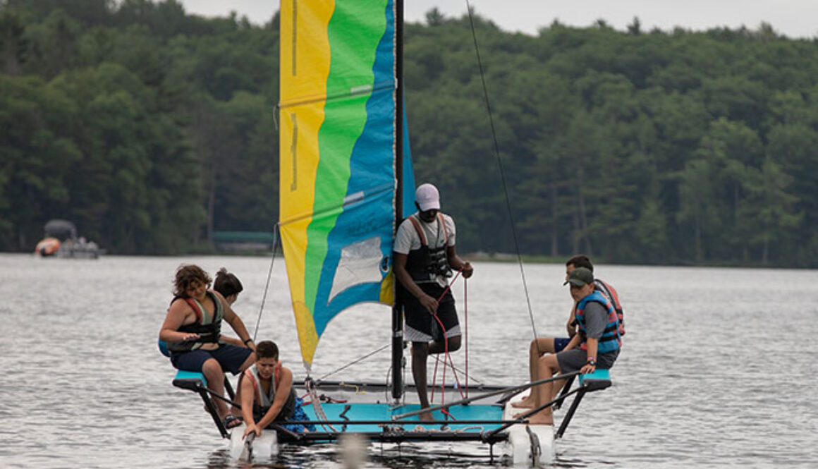 A group of campers and an instructor at North Star Camp for Boys steer a sailboat on Spider Lake.